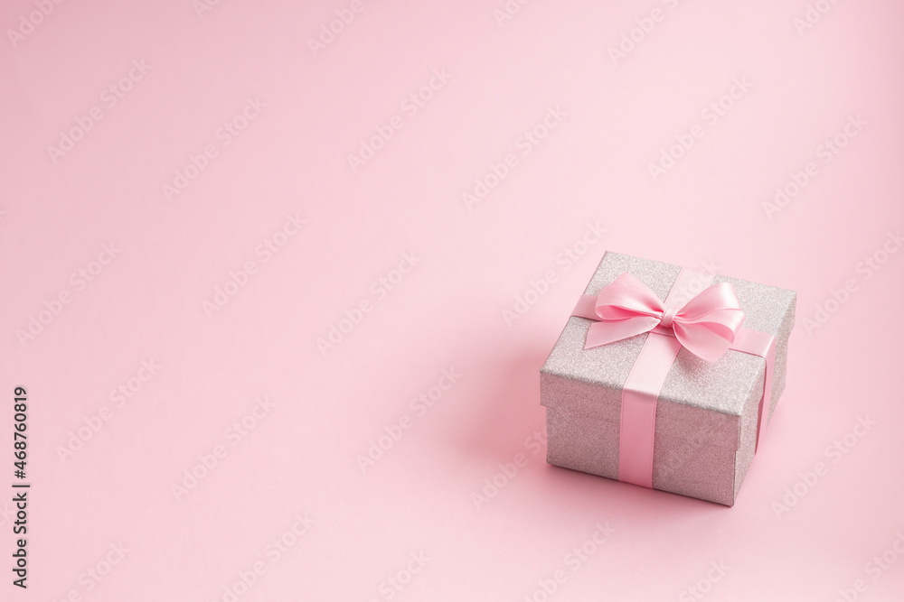 Silver glitter gift box with pink ribbon bow on pink background. Christmas, Valentine's day or birthday concept. Silver glitter gift box with pink ribbon bow on pink background. Christmas, Valentine's day or birthday concept.