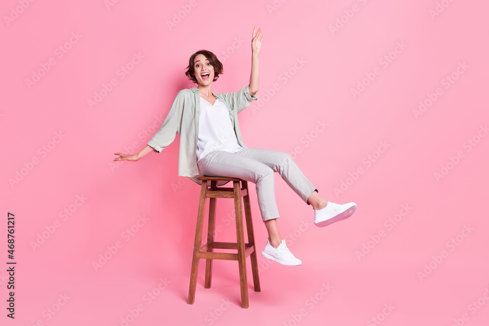 Full length photo of funny bob hairdo millennial lady sit dance wear grey green look isolated on pink background Full length photo of funny bob hairdo millennial lady sit dance wear grey green look isolated on pink background
