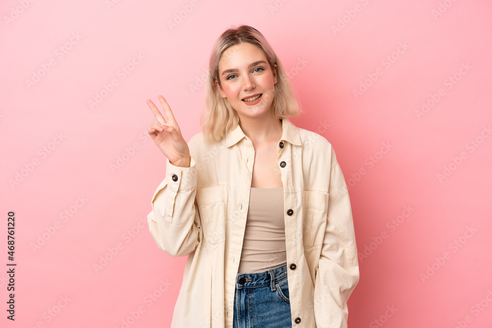 Young caucasian woman isolated on pink background smiling and showing victory sign Young caucasian woman isolated on pink background smiling and showing victory sign