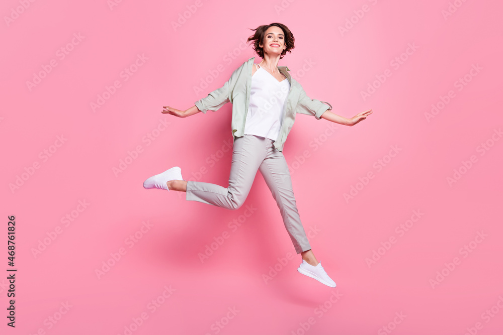 Full size photo of funky young lady jump wear grey green suit isolated on pink color background Full size photo of funky young lady jump wear grey green suit isolated on pink color background