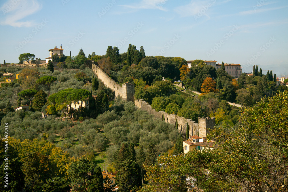 View on old city wall in Florence - Firenze. Landscape with green trees and gardens. Aerial view from above with blue sky.