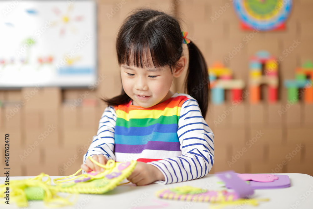 young girl sewing pad craft using plastic needle and yarn at home young girl sewing pad craft using plastic needle and yarn at home