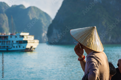 HA LONG BAY, VIETNAM, JANUARY 6 2020: Vietnamese man smoking with a traditional hat