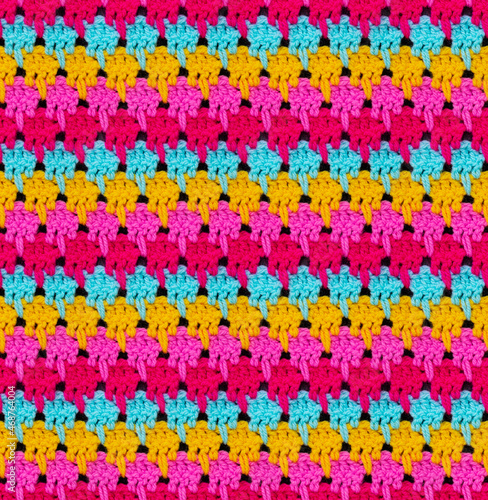 Seamless knitted texture. The pattern is crocheted from bright multi-colored acrylic yarn. African motives.