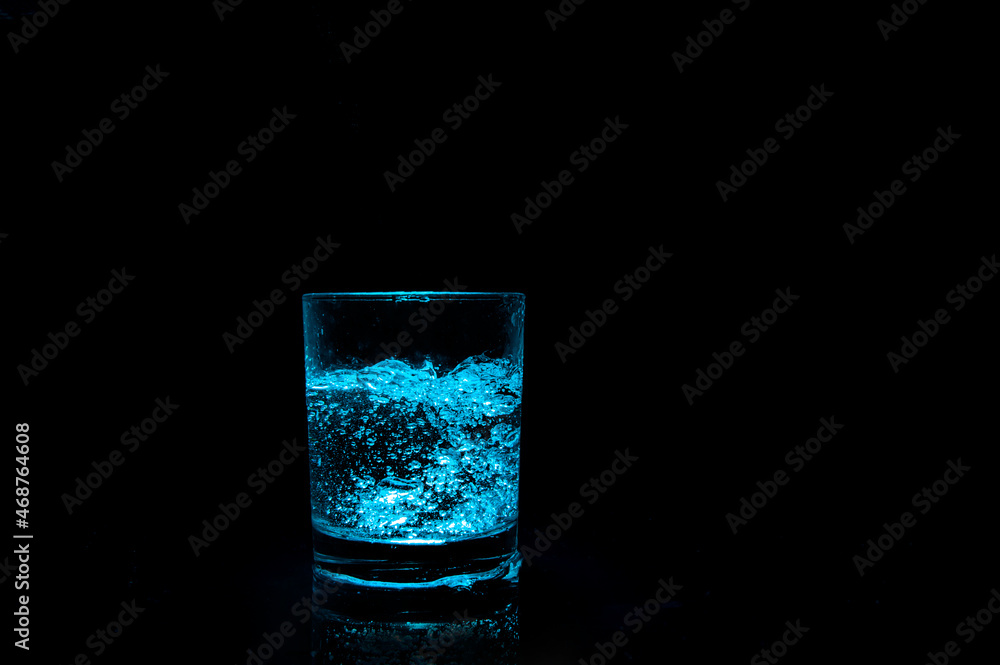 glass with ice cubes and bottom illumination on dark background glass with ice cubes and bottom illumination on dark background