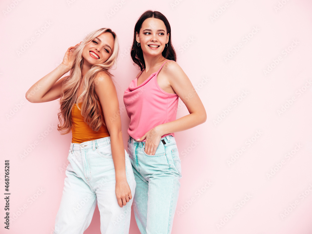 Two young beautiful smiling brunette hipster female in trendy summer clothes. Sexy carefree women posing near pink wall. Positive models having fun. Cheerful and happy Two young beautiful smiling brunette hipster female in trendy summer clothes. Sexy carefree women posing near pink wall. Positive models having fun. Cheerful and happy
