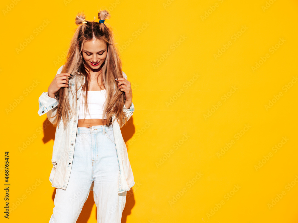 Portrait of young beautiful smiling blond female in trendy summer clothes. Sexy carefree woman posing near yellow wall in studio. Positive model having fun indoors. Cheerful and happy Portrait of young beautiful smiling blond female in trendy summer clothes. Sexy carefree woman posing near yellow wall in studio. Positive model having fun indoors. Cheerful and happy