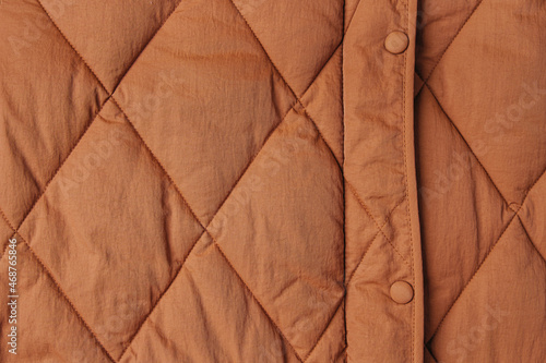 Close-up on brown puffer jacket texture. Quilted fabric background
