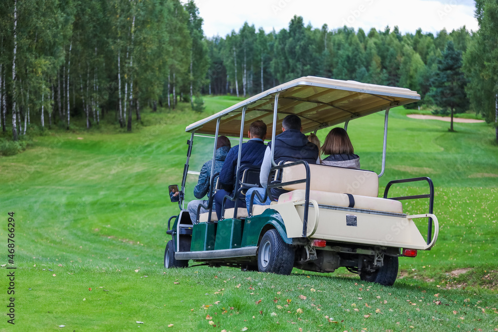 Electric golf car on the green field with passengers. High quality photo