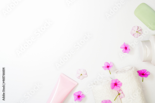 Spa white background pink flowers and a bottle of shampoo, soap and cream lotion. White towel rolls. Copy space in the center, empty space for text