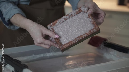 A woman holding a frame for making paper sheets from recycled paper. Selective focus. Household hobby, paper recycling. The concept of zero waste, recycling, ecology