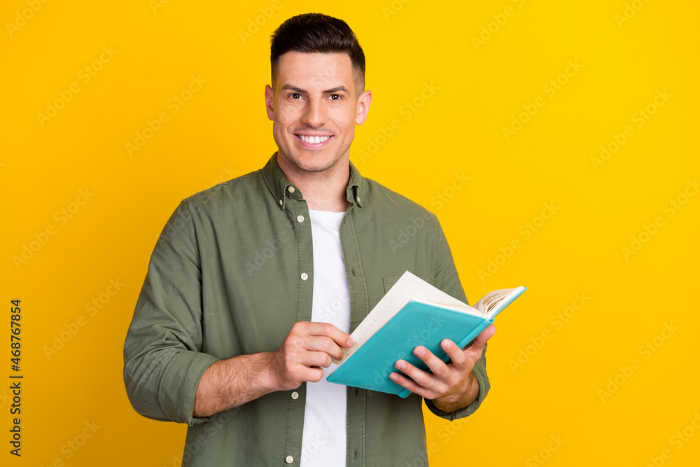 Photo portrait man smiling keeping book reading novel isolated vibrant yellow color background Photo portrait man smiling keeping book reading novel isolated vibrant yellow color background