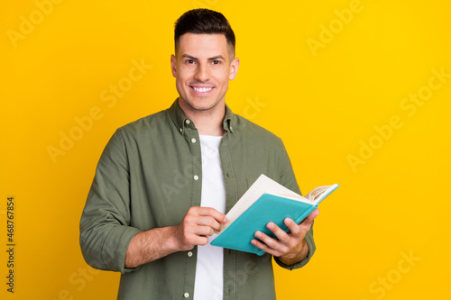 Photo portrait man smiling keeping book reading novel isolated vibrant yellow color background