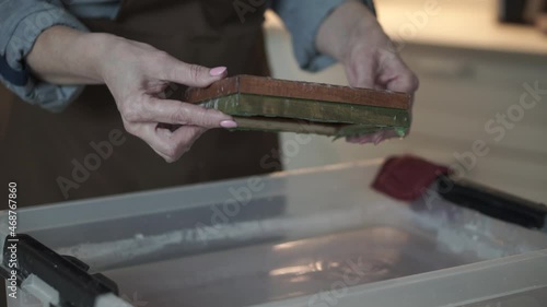 A woman holding a frame for making paper sheets from recycled paper. Selective focus. Household hobby, paper recycling. The concept of zero waste, recycling, ecology
