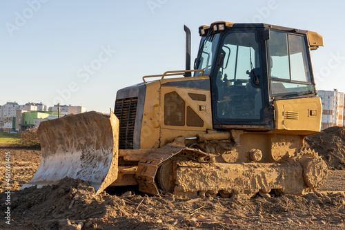 yellow bulldozer levels the ground in front of a hospital development for covid treatment