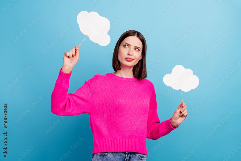 Photo of doubtful pretty young lady wear pink pullover holding two speaking bubbles empty space isolated blue color background Photo of doubtful pretty young lady wear pink pullover holding two speaking bubbles empty space isolated blue color background