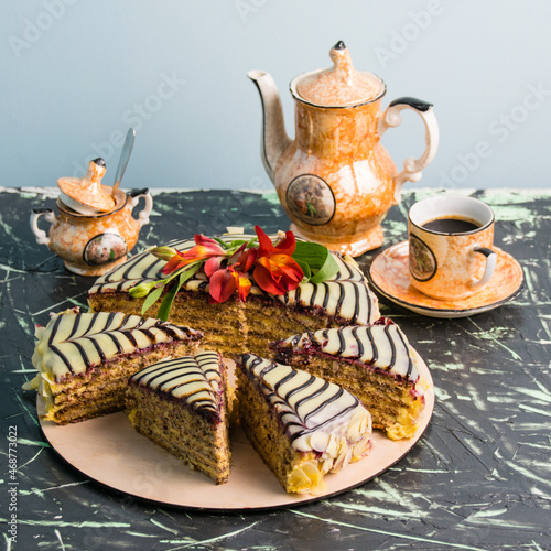 Sliced cake with cream  almonds  black and white chocolate on a wooden substrate on the table  a cup of coffee  close up copy space  holiday concept