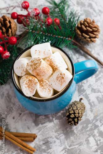 Christmas cocoa drink with chewing marshmallows and cinnamon in a blue cup on a light background, close up, flatlay