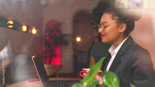 dark-skinned girl works for a laptop in a cafe dreams of the new year
