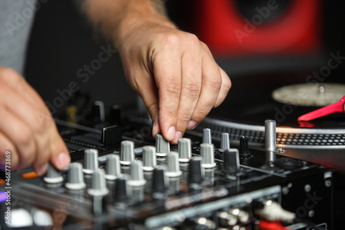 Hands of dj playing music in night club on party