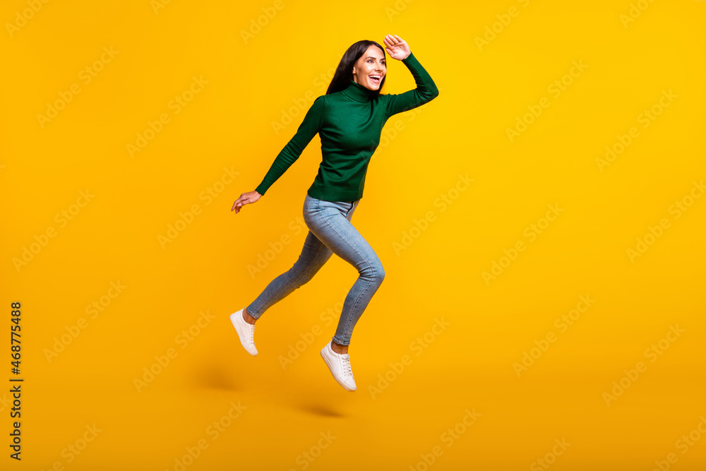 Full body profile side photo of brunette lady wear green sweater jeans look empty space jump run isolated on yellow color background