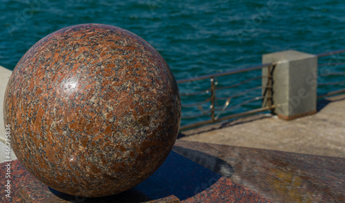 Big red decorative granite ball on embankment of Novorossiysk. The polished ball against blue Black Sea.