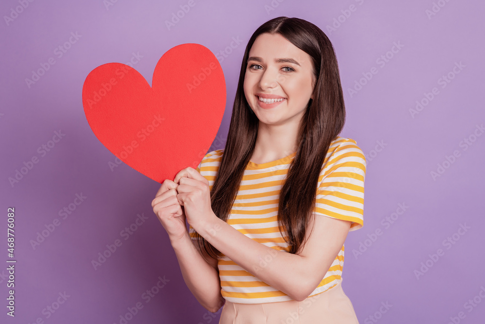 Portrait of adorable sweet lady showing big red paper heart white smile on purple background Portrait of adorable sweet lady showing big red paper heart white smile on purple background