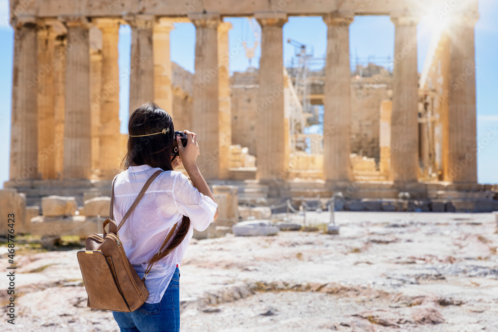 A female tourist is taking photos of the Parthenon Temple at the Acropolis of Athens, Greece, during her sightseeing city trip