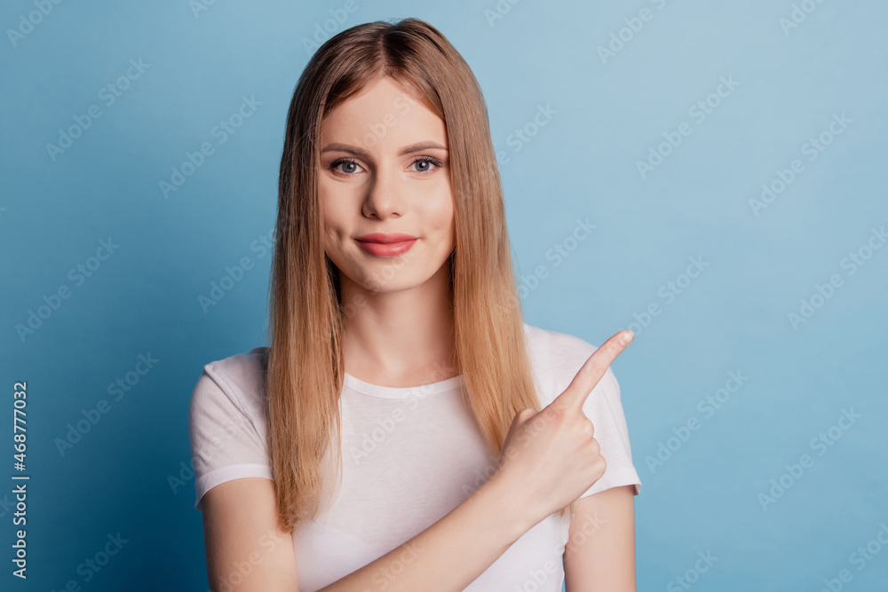 Photo of charming promoter lady direct finger empty space promoting novelty on blue color background Photo of charming promoter lady direct finger empty space promoting novelty on blue color background