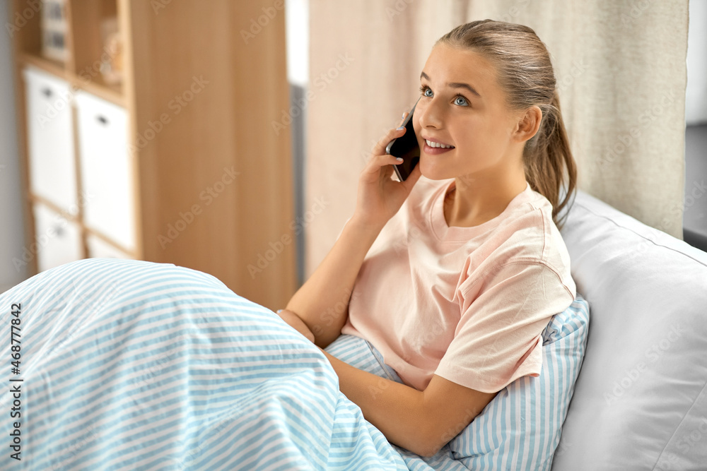 people, communication and technology concept - happy smiling girl with smartphone calling in bed at home people, communication and technology concept - happy smiling girl with smartphone calling in bed at home