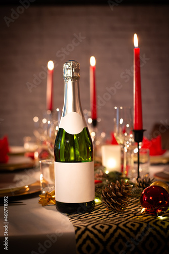 champagne bottle on a christmas holiday festive party table with wine glass on a red and gold shiny decoration