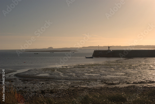 view over Lindisfarne harbour to Bamburgh castle in sunset