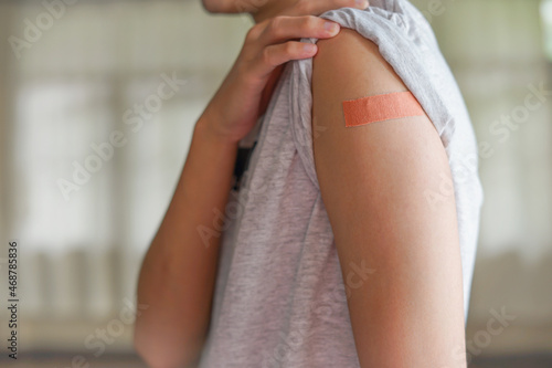 a man pull the sleeve at shoulder show adhesive bandage plaster on his arm after Covid-19 vaccine injection. Free Covid-19 vaccinnation  coronavirus vaccination campaign concept.