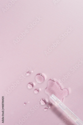 Vertical shot of a small tube and face oil on a pink surface © YuliiaMazurkevych