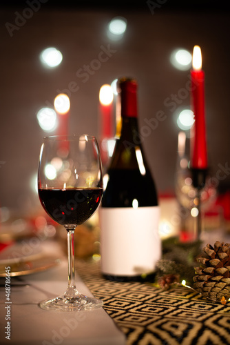 red wine bottle on a christmas holiday festive party table with wine a glass on red and gold shiny decoration