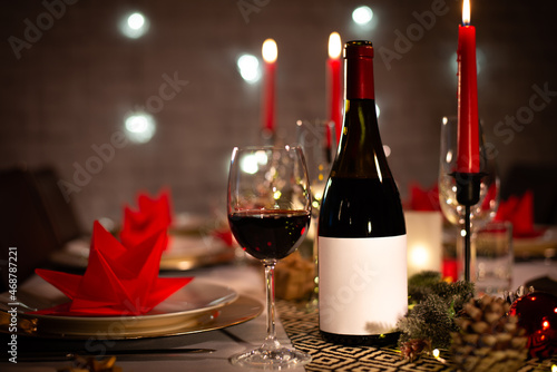 red wine bottle on a christmas holiday festive party table with wine a glass on red and gold shiny decoration
