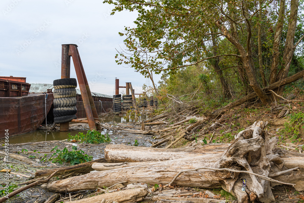 Large Driftwood Logs and Docked Barges along the Mississippi River in New Orleans, Louisiana, USA Large Driftwood Logs and Docked Barges along the Mississippi River in New Orleans, Louisiana, USA