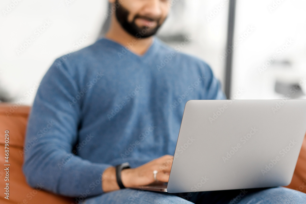 Cropped picture of Indian bearded man using laptop, Hispanic guy is typing on the keyboard, answering emails, multiracial male freelancer in casual wear working remotely from home Cropped picture of Indian bearded man using laptop, Hispanic guy is typing on the keyboard, answering emails, multiracial male freelancer in casual wear working remotely from home