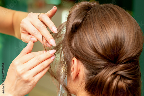 Close Up hairdresser stylist makes hairstyle for a young woman in a beauty salon