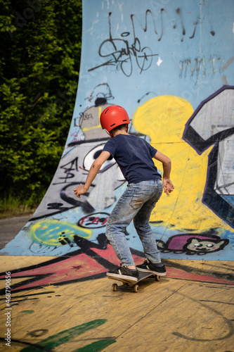 Junge mit Skateboard im Skatepark in der Halfpipe voll Grafitti beim pushen üben