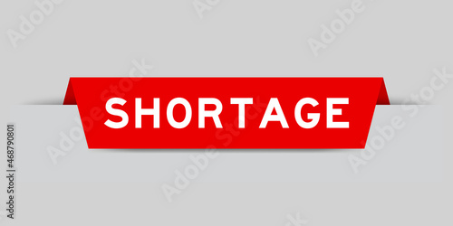 Red color inserted label with word shortage on gray background