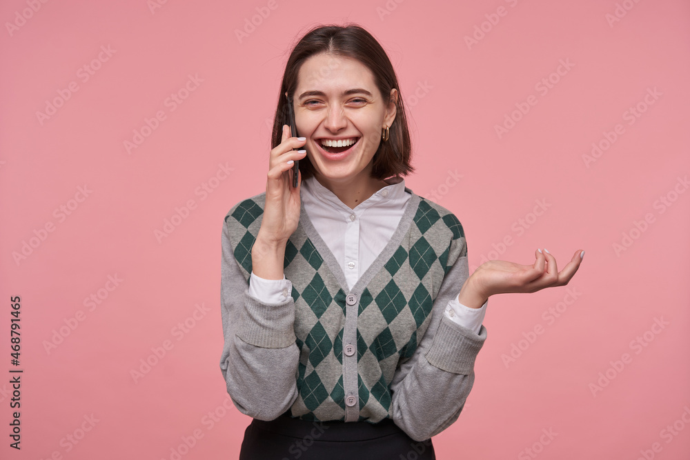 Indoor shot of young positive brunette woman, smiling broadly while talking on phone with her friend. Isolated over pink background Indoor shot of young positive brunette woman, smiling broadly while talking on phone with her friend. Isolated over pink background