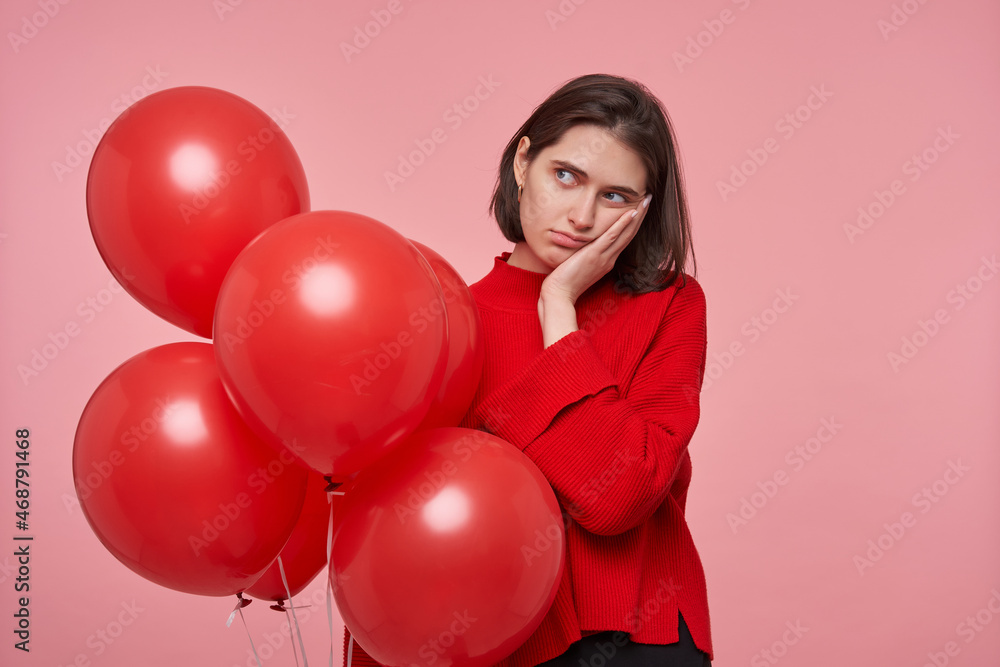 Indoor portrait of young negative, sad and bored female. Isolated over pink background