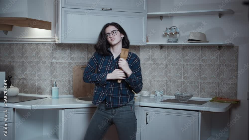teen brunette girl dancing and singing in the kitchen, good mood, puts on a hat teen brunette girl dancing and singing in the kitchen, good mood, puts on a hat