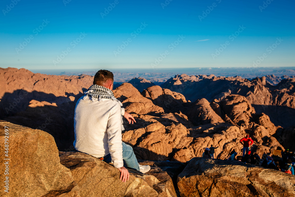 A man sits facing the rising sun on Mount Sinai in Egypt. A man sits facing the rising sun on Mount Sinai in Egypt.