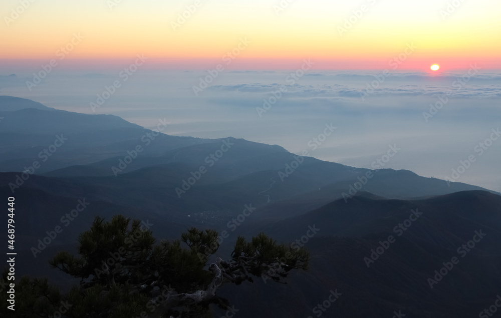 Sunrise seen from the mountains. Sun on the horizon above the clouds