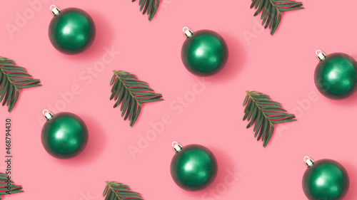 Fototapeta Naklejka Na Ścianę i Meble -  Trendy New year pattern with green Christmas baubles and fir branches on pastel pink background.