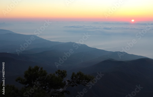 Sunrise seen from the mountains. Sun on the horizon above the clouds © Elena