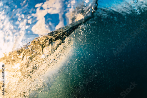 Wave underwater and bubbles with sunrise or sunset light.