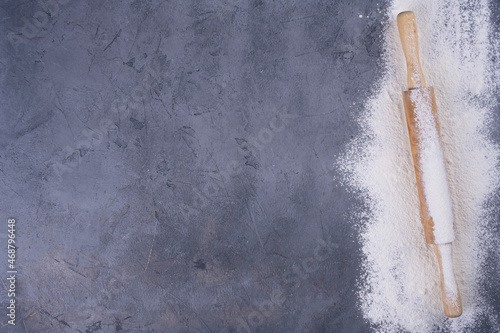 flour and wooden rolling pin on a gray concrete stone table